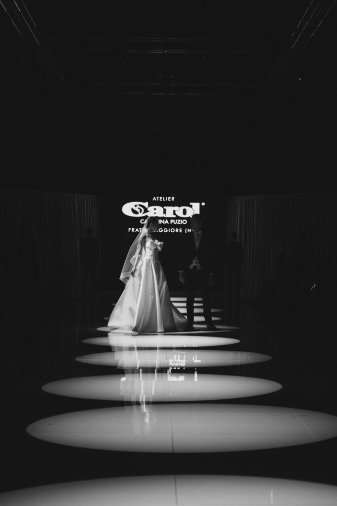 Sposa e sposo in controluce sulla passerella della sfilata Atelier Carol